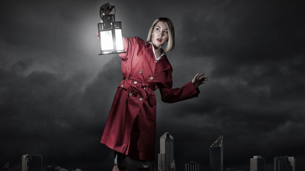 woman in red holding a lantern in the dark