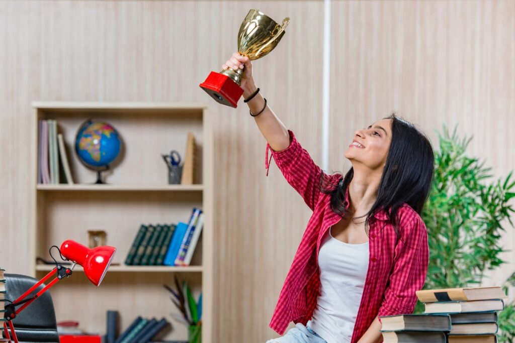 Woman surrounded by books holding an award